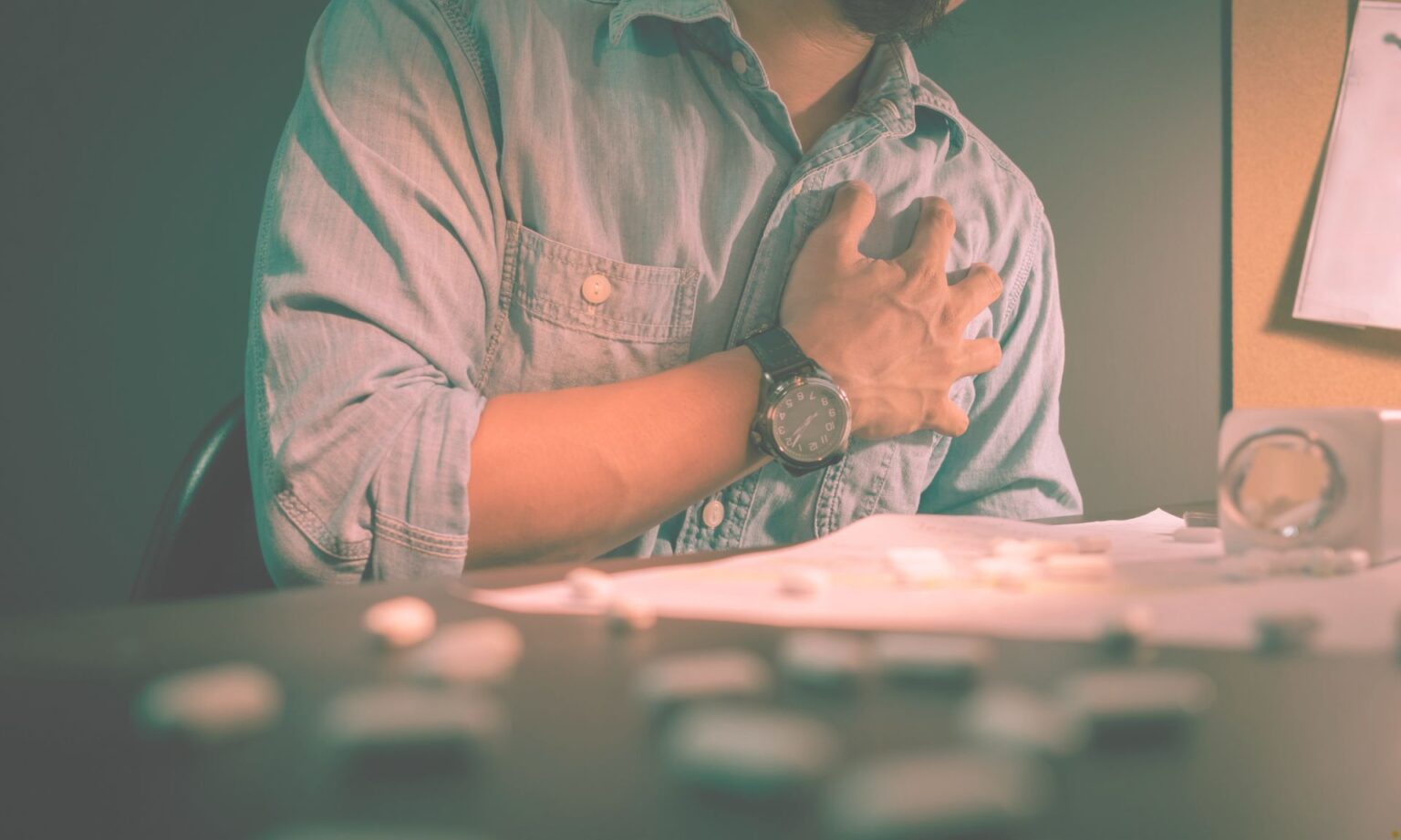 lower the risk of heart attack - A close-up shot of a tired office worker holding his chest, appearing distressed, symbolizing the physical strain and stress of working overtime.