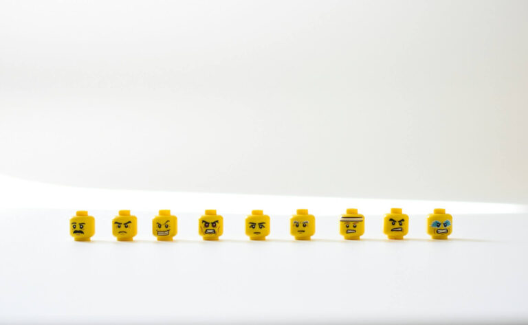 Row of yellow LEGO heads displaying different intense facial expressions, symbolizing the variety of emotions involved in learning anger management tricks.