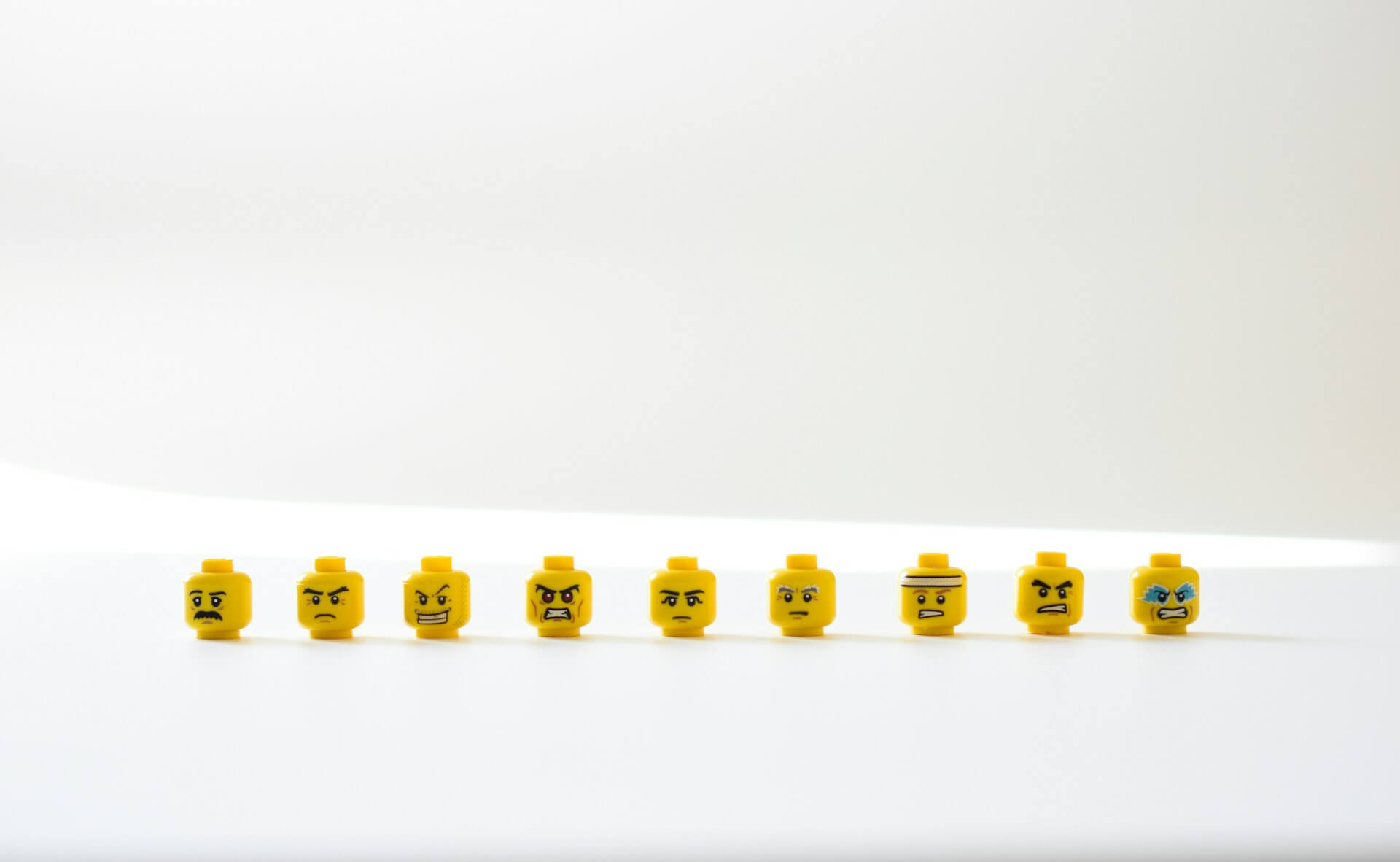 Row of yellow LEGO heads displaying different intense facial expressions, symbolizing the variety of emotions involved in learning anger management tricks.