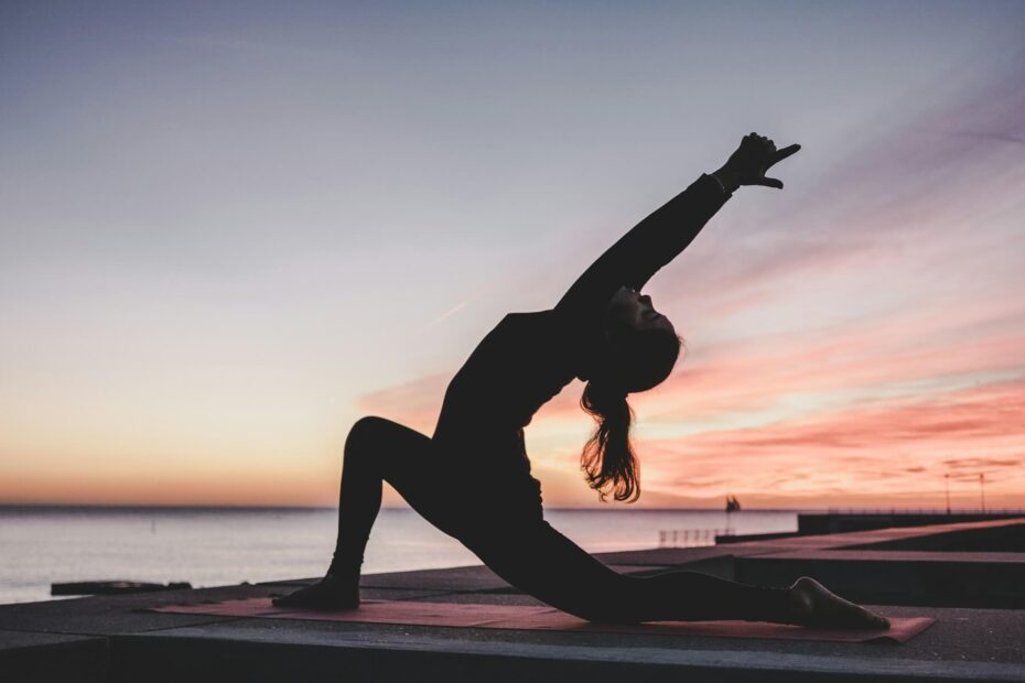 Person practicing yoga at sunrise, stretching in a deep lunge pose, symbolizing peaceful and intentional daily yoga rituals.