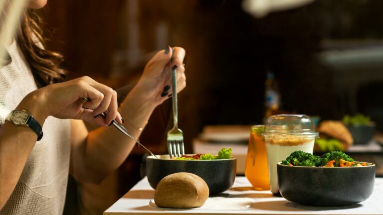 Person eating a healthy meal with vegetables, salad, and whole foods, representing small nutrition tweaks for better wellness.