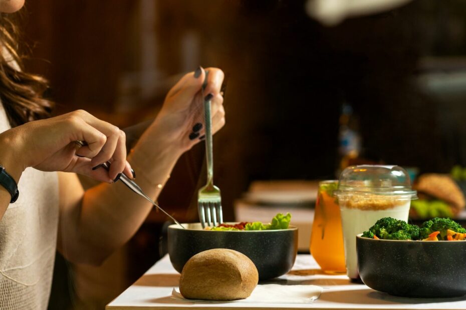 Person eating a healthy meal with vegetables, salad, and whole foods, representing small nutrition tweaks for better wellness.