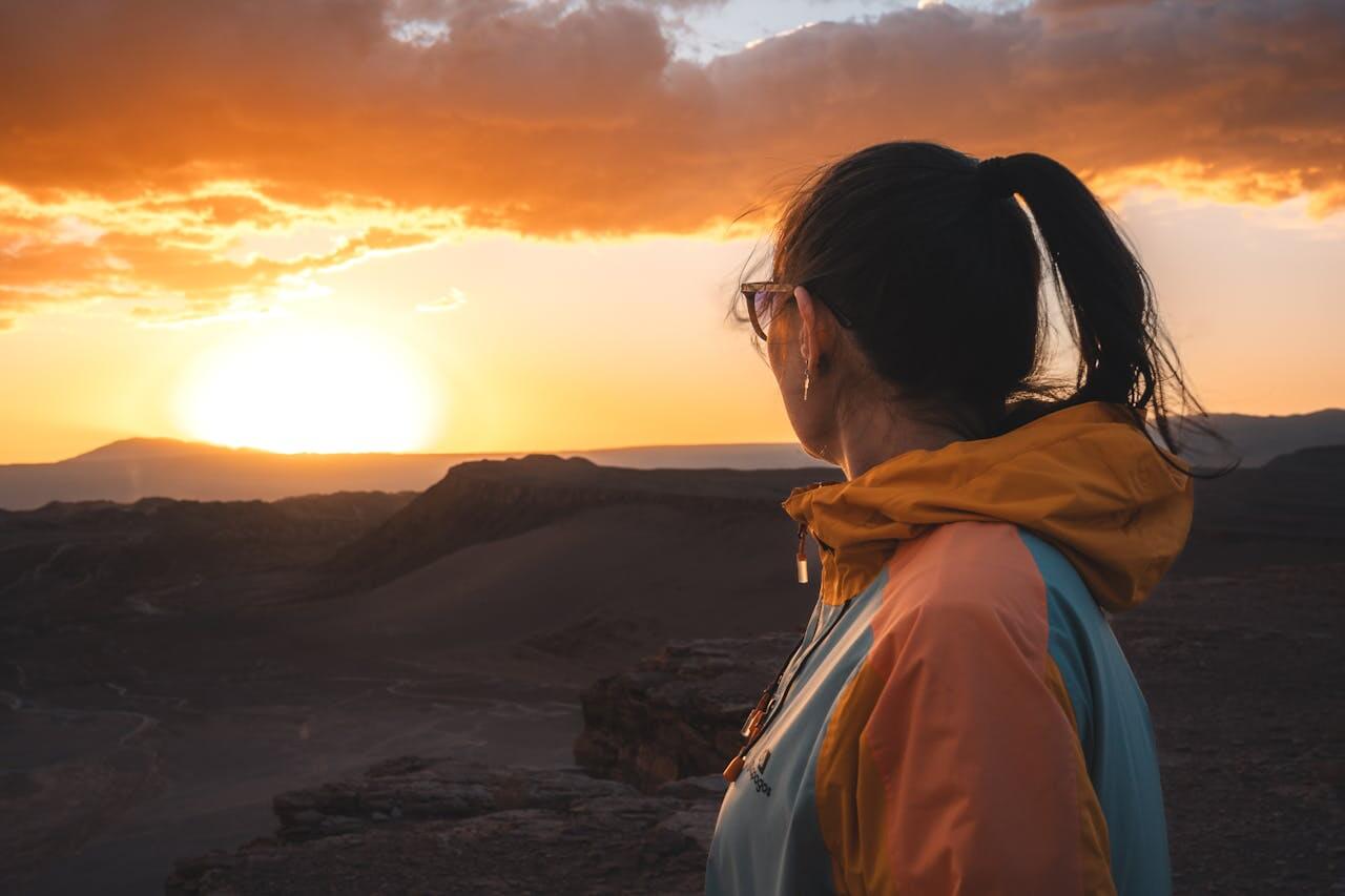 Person standing on a mountain at sunset, reflecting quietly and embracing trust in the journey ahead